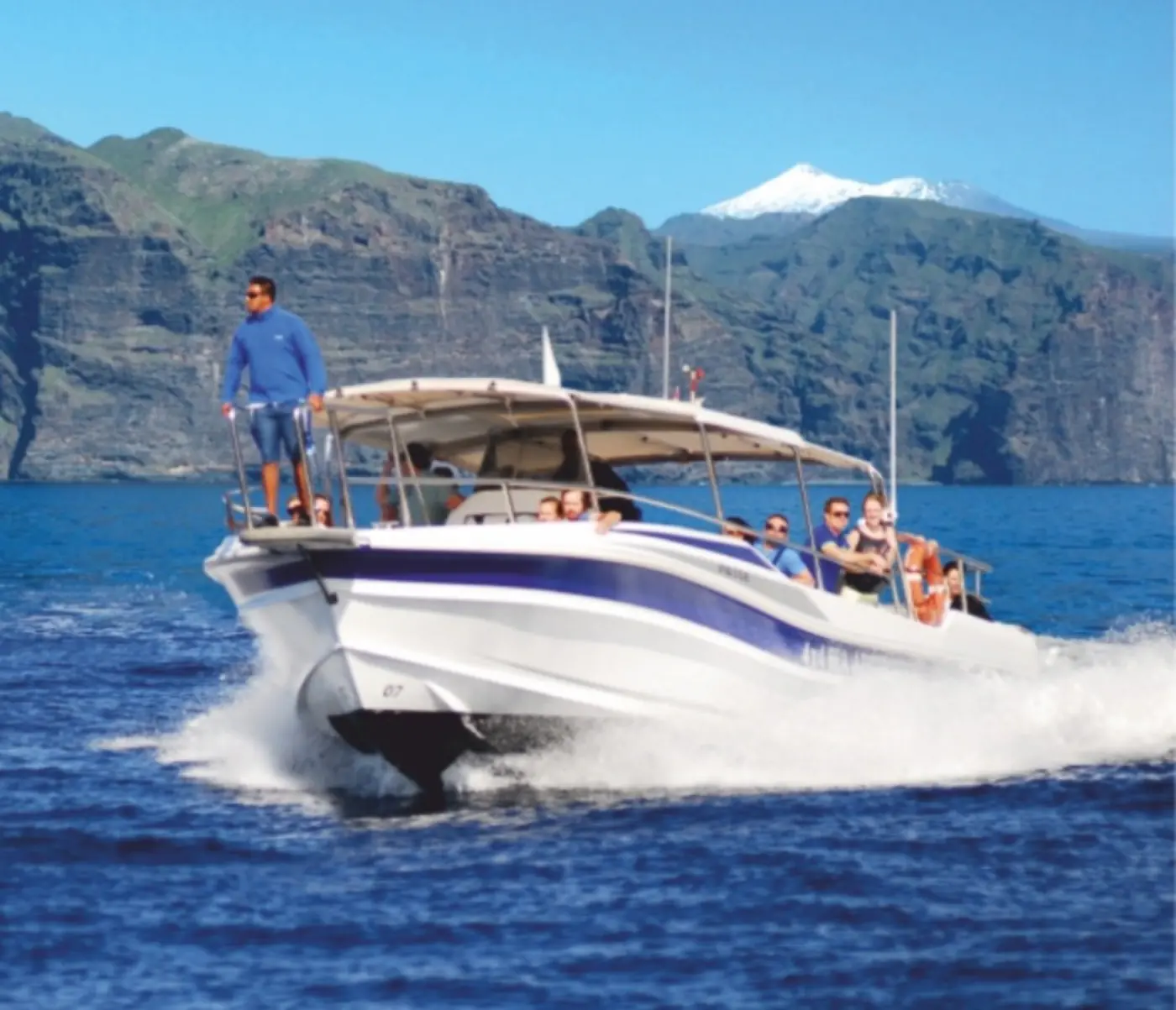 Barco de avistamiento navegando frente a los acantilados de Los Gigantes con el Teide al fondo