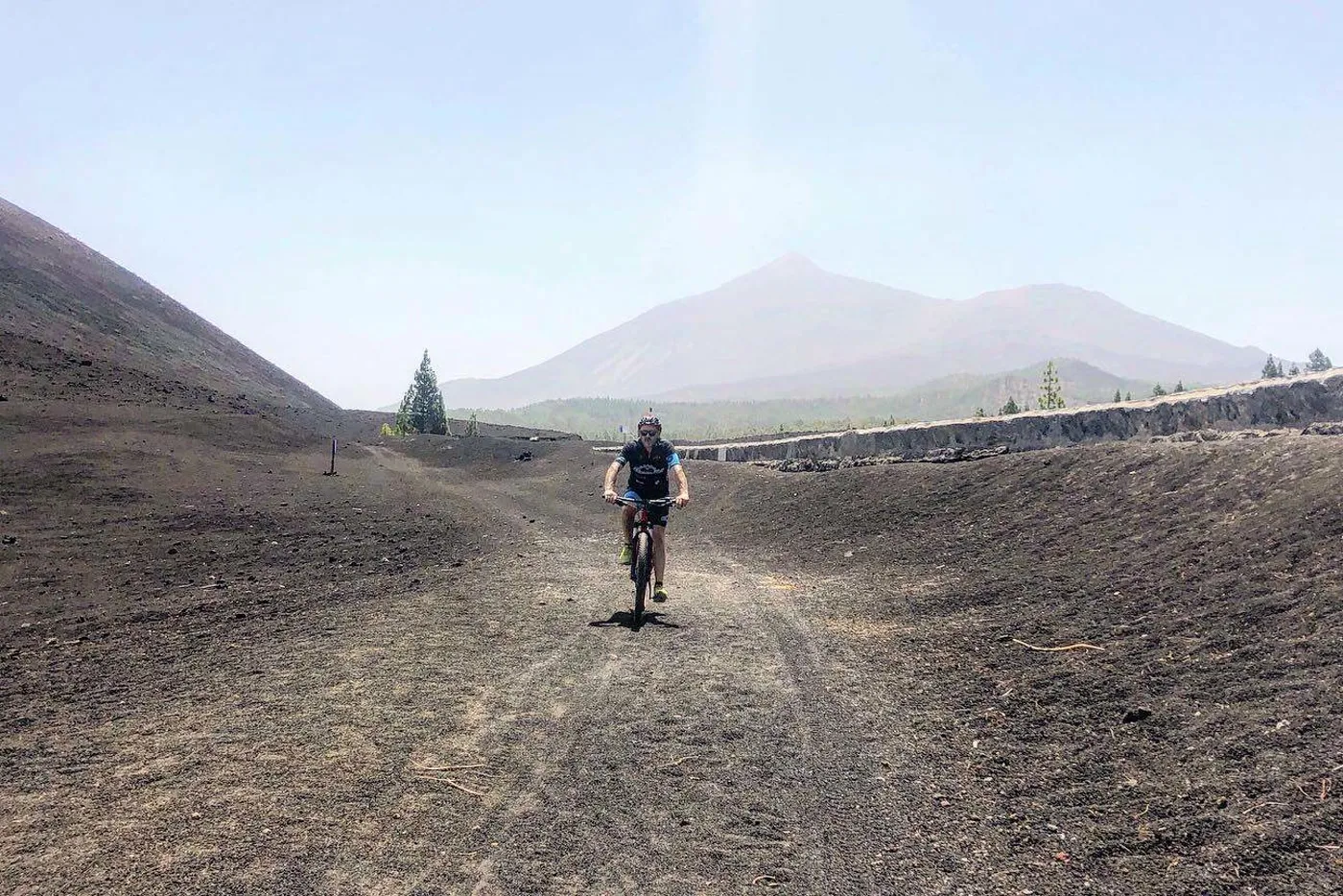 Ciclista de montaña en una pista volcánica con el Teide al fondo