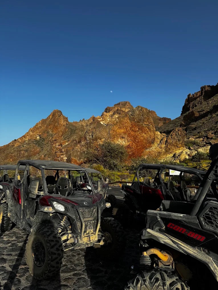 Buggies parados ante un roque volcánico al atardecer