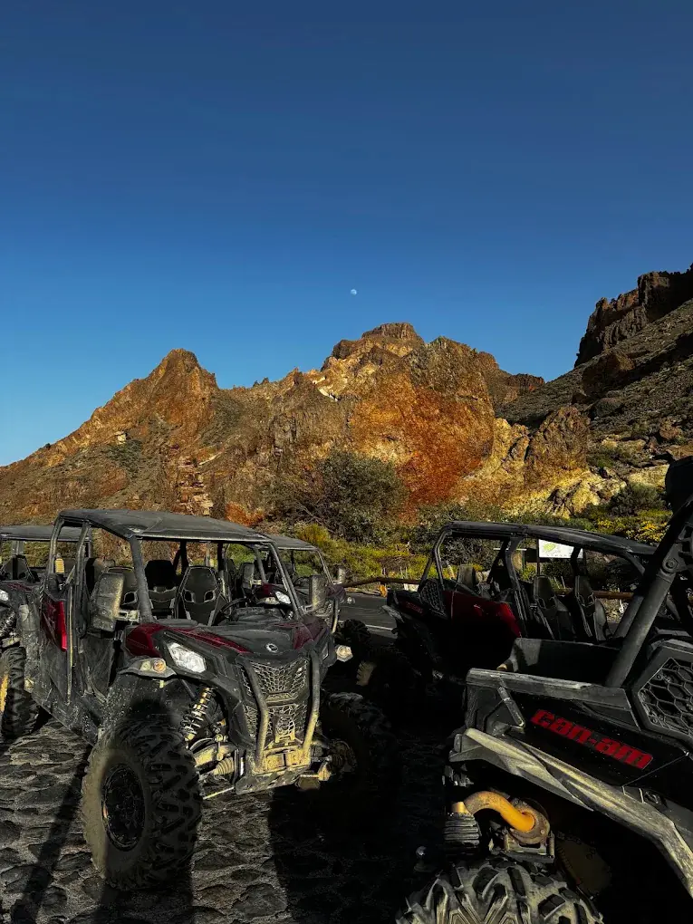 Buggies parados ante un roque volcánico al atardecer