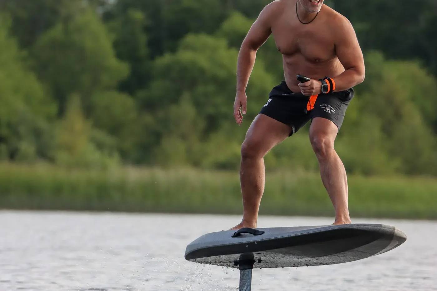 Persona de pie sobre una tabla de eFoil volando sobre el agua